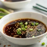 Sauce soja sucrée maison luisante dans un bol blanc avec garnitures fraîches sur fond granit