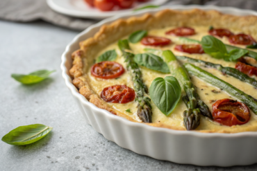 Quiche aux asperges fromage: la recette facile et rapide ! 4 Quiche aux asperges fromage with fresh basil and roasted tomatoes on white dish.